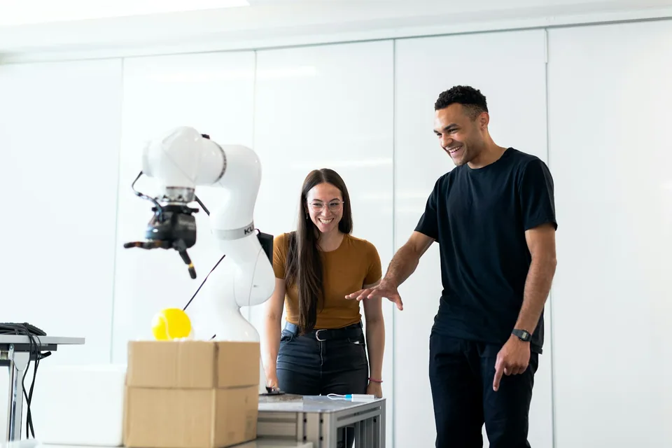 Engineers working beside a robotic arm